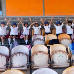 Students sat in chairs with arms in the air