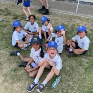 Young students with blue hats sat on the grass
